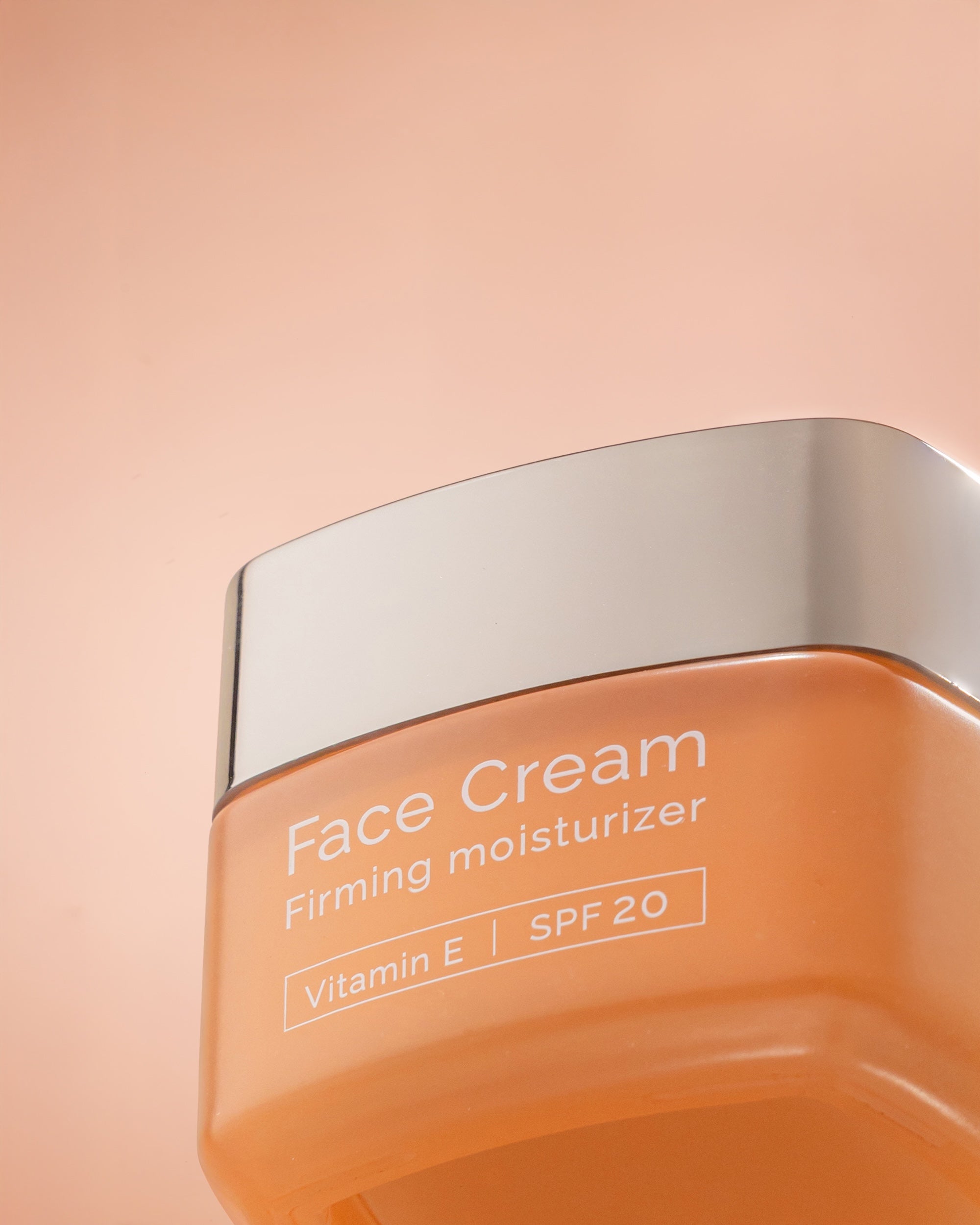 Face cream with SPF20 jar with silver lid on a peach background