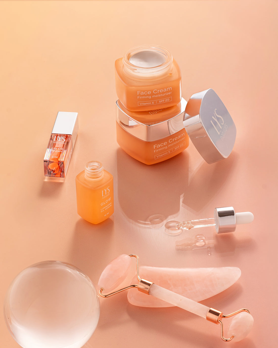 LYS Naturals Face Cream with SPF 20, Lip Oil Repair, GLOW Face Oil, and a roller on a peach background.